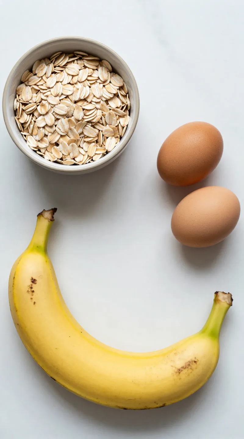 Ripe banana, oats, and eggs flat lay on marble counter