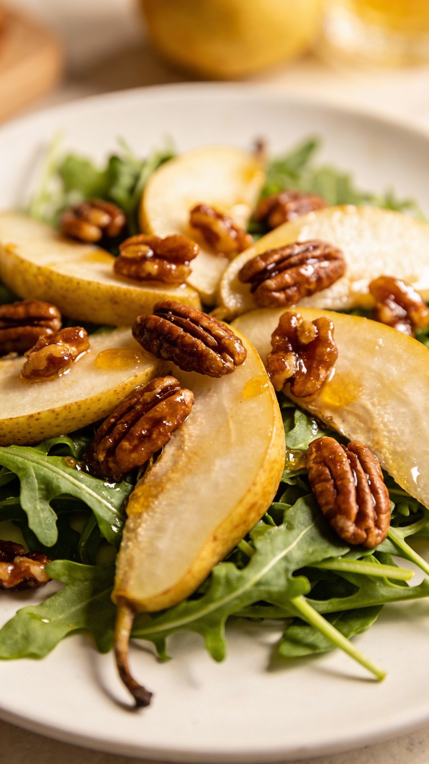 pear arugula salad with candied pecans on white plate