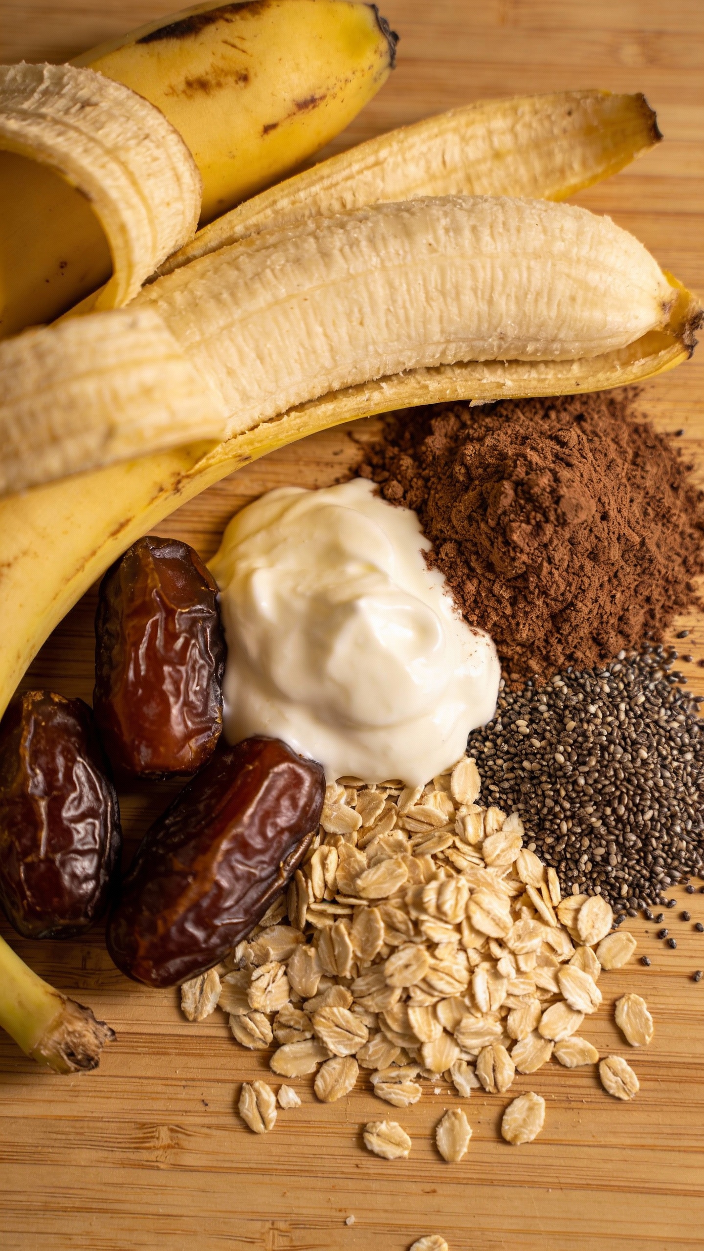 overhead ingredients: ripe bananas, dates, cocoa, oats, chia, yogurt