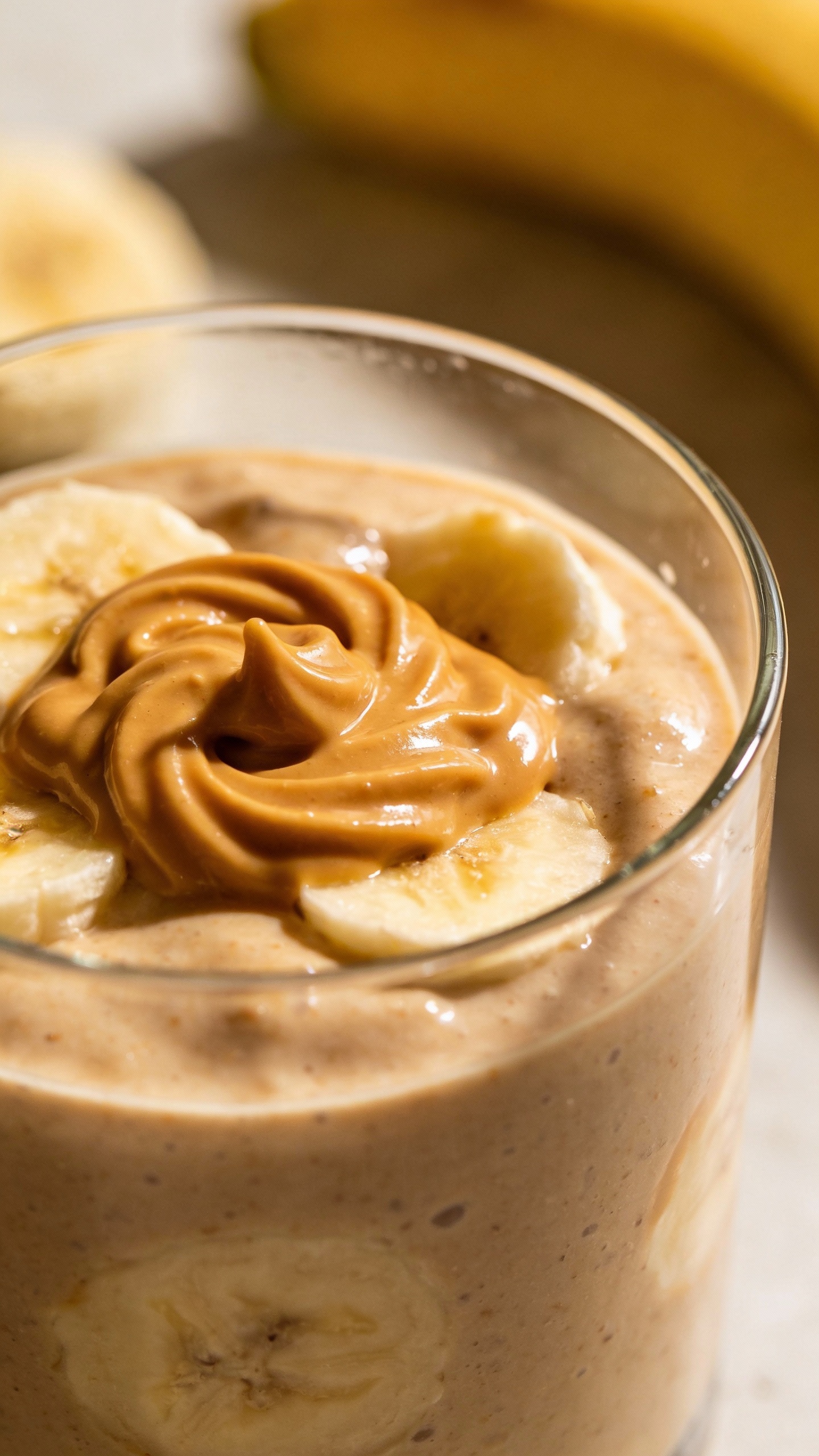 Peanut butter banana smoothie in clear glass, soft daylight