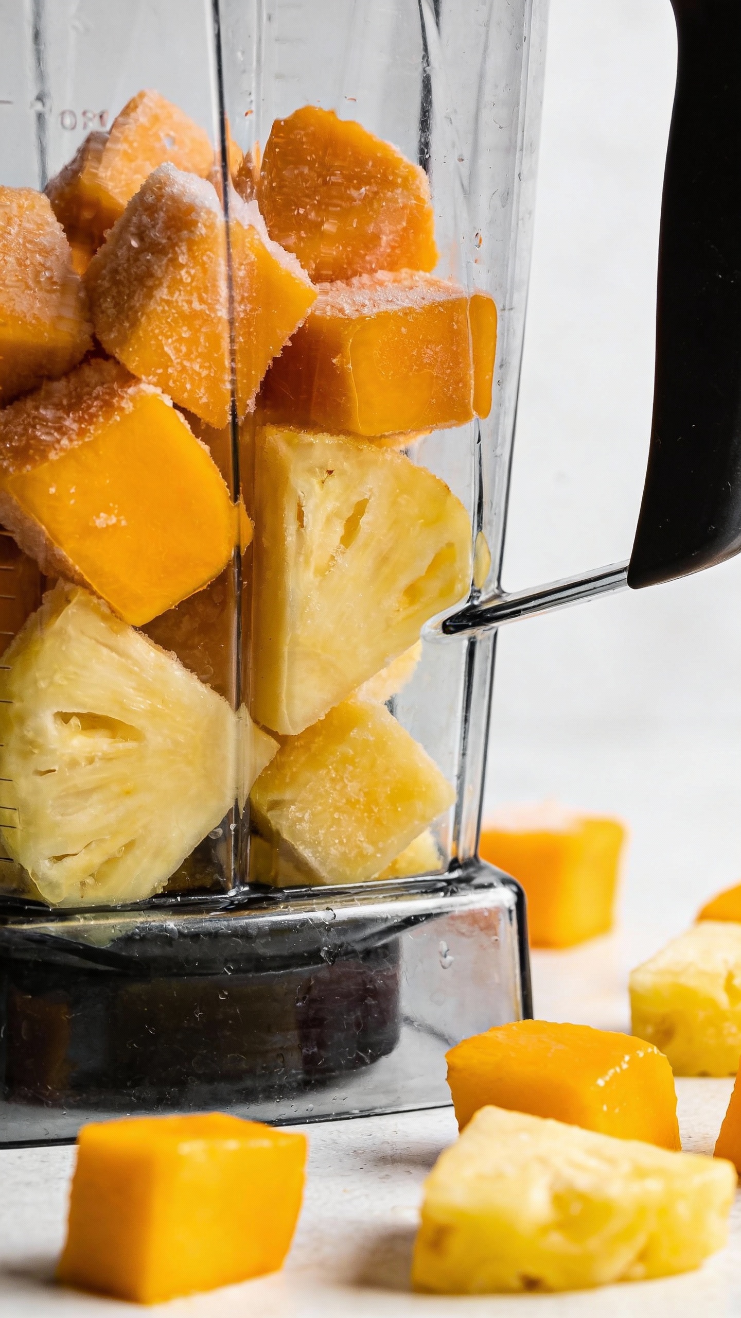 frozen mango and pineapple chunks with blender, bright natural light
